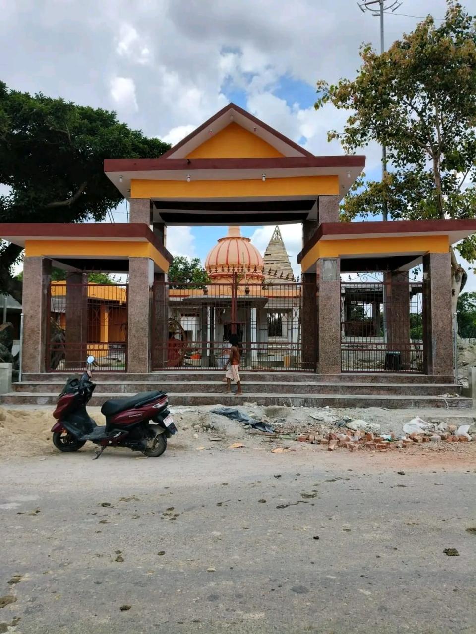 The newly built entrance gateway to Manara Mahadev Mandir, with construction sand and brick still stacked along the road outside